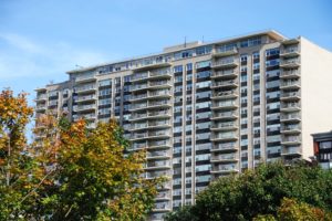 A tall residential building with balconies under a clear blue sky.