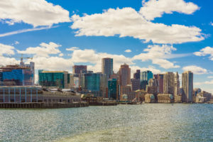 City skyline with modern buildings by the water under a blue sky.