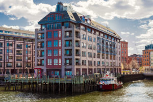 A large modern building by the water with a docked boat.
