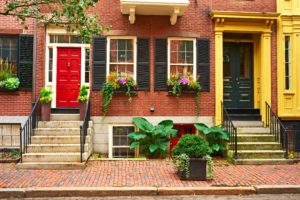 Charming brick townhouse with colorful doors and flower boxes.