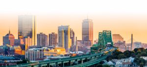 City skyline at sunset with modern buildings and a bridge in the foreground.