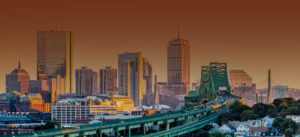 City skyline with a train crossing a bridge at sunset.