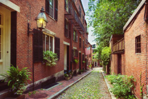 Charming brick alleyway with lanterns and greenery on a sunny day.